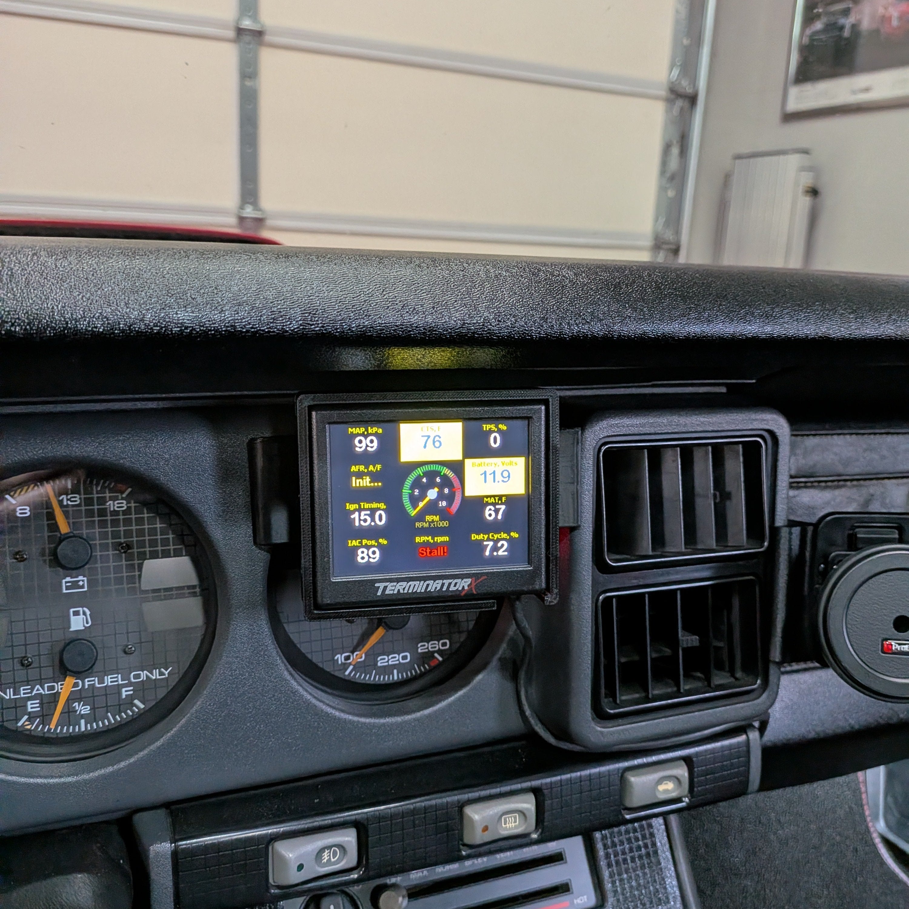 Car dashboard with digital display and various controls in a garage setting